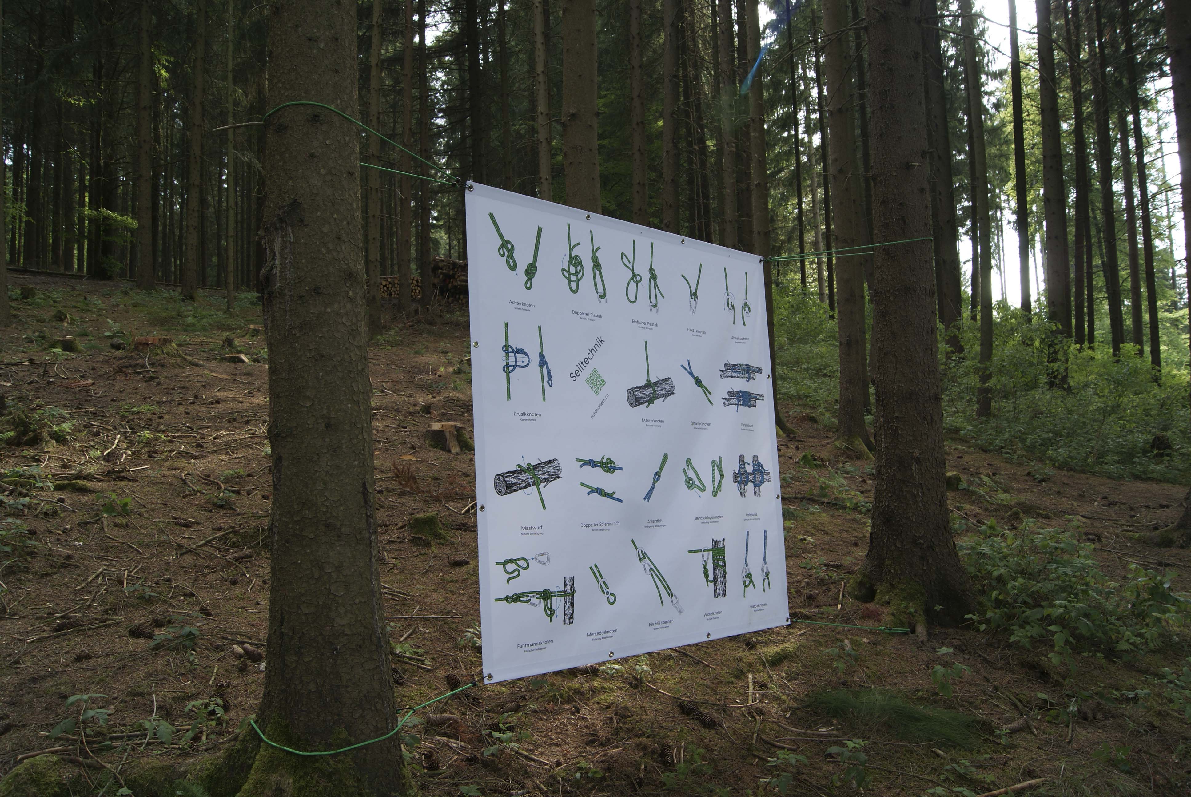 eine Infotafel zur Seiltechnik hängt mitten im Wald