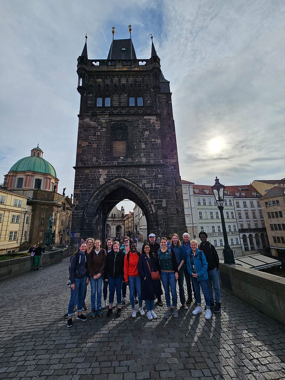 Unter dem Torbogen der Geschichte: Die Gruppe sammelt sich auf der Karlsbrücke, bereit, die historischen Pfade Prags zu erkunden und gemeinsam neue Wege zu gehen.